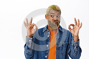 Close up of stylish hipster guy shows okay sign. Handsome african american man with yellow beard and hairstyle, makes ok