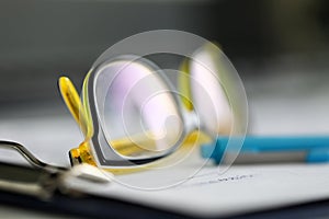 Close-up stylish reading glasses lie on documents