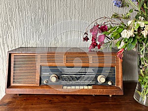 Close up of stylish vintage radio on wooden table against white wall