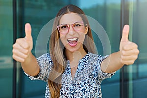 Close up of successful winning young woman with thumbs up outdoors