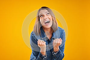 Close up of successfull woman in denim jacket over yellow background