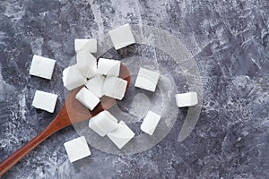 Close up of sugar cube on wooden spoon.