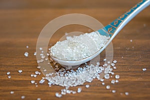 Close up of sugar in spoon on a wooden table. Copy space provided