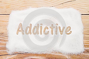 Close-up of sugar with text Addictive on weathered wood backgrou