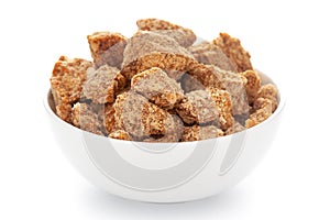 Close-Up of sugarcane jaggery piece in white ceramic bowl over white background