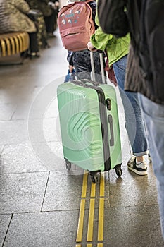 Close-up of suitcase, luggage in hands of girl traveler waiting transport