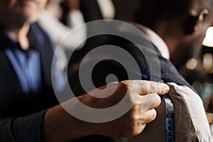 Close up of suitmaker doing fitting