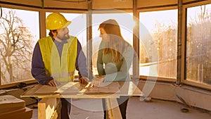 CLOSE UP Sunrise illuminates the room as owner and architect discuss floor plans