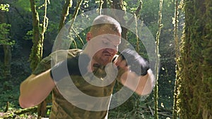 close-up, super slow motion. male boxer training in the forest, boxing the trunk of a large tree