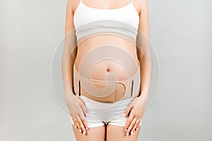 Close up of supporting orthopedic bandage against backache on pregnant woman in underwear at gray background with copy space.