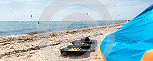 Close-up surf board and kite equipment on sand beach shore watersport spot on bright sunny day against sea ocean coast