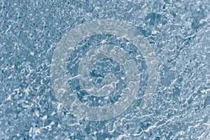 Close-up of the surface of a fragment of a glacier with a structure of stripes and bubbles. Ice blue texture to the