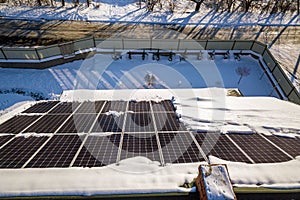 Close up surface of a house roof covered with solar panels in winter with snow on top. Energy efficiency and maintenance concept