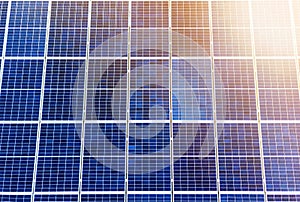 Close-up surface of lit by sun blue shiny solar photo voltaic panels. System producing renewable clean energy. Renewable