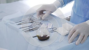 Close-up of surgeon preparing instruments for surgery. Action. Professional surgeon prepared various types of clips and