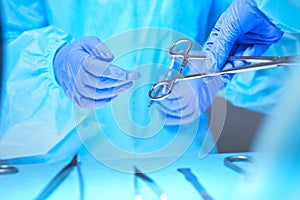 Close-up of of surgeons hands at work in operating theater toned in blue