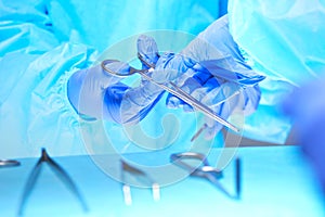 Close-up of of surgeons hands at work in operating theater toned in blue