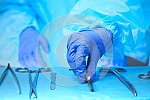 Close-up of of surgeons hands at work in operating theater toned in blue