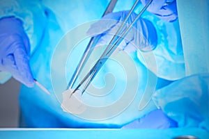 Close-up of of surgeons hands at work in operating theater toned in blue