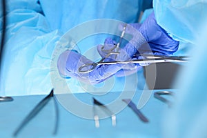 Close-up of of surgeons hands at work in operating theater toned in blue