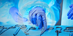 Close-up of of surgeons hands at work in operating theater toned in blue