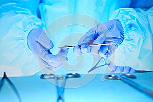 Close-up of of surgeons hands at work in operating theater toned in blue