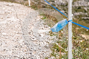 Close up a surgical mask discarded on a mountain path