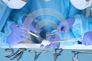 Close up of surgical tools while group of surgeons at work in operating theater