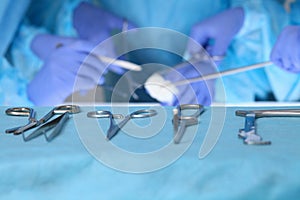 Close up of surgical tools while group of surgeons at work in operating theater