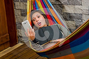 Close up of surprised young beautiful woman relaxing in a hammock and taking a selfie with her tablet while is holding a