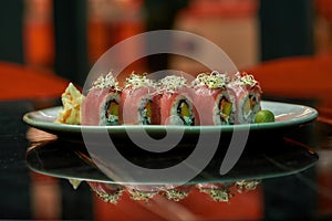 Close up of sushi rolls with raw tuna fish on white plate on a table of Japanese restaurant