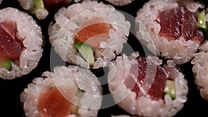 Close up sushi rolls rotating. Japanese food avocado, salmon, tuna.