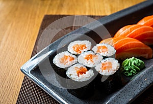 Close up Sushi Rolls Set with wasabi,  on a Black plate on wooden table in the restaurant.