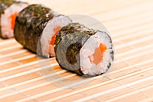 Close-up of sushi in row on bamboo mat