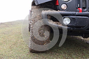 Close up of suv car with dirty wheels in field.