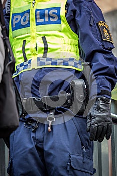 Close up of Swedish police officer wearing a luminous yellow green vest with police text.