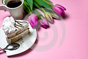 Close-up sweet black coffee cake and lilac tulips on a light pink background, close-up. Greeting card with place for text, copy