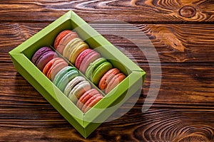 Close up. Sweet and colorful french macarons in a light green box on a wooden brown background. Copy space