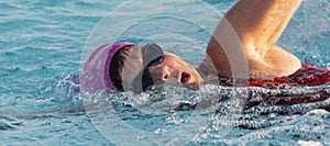 Close up of a swimmers face as she takes a breath while swimming laps in a pool
