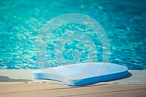 Close up swimming foam board lie on edge of swimming pool with blue water background.