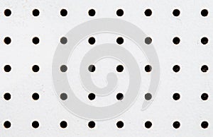 Close-up of symetrical holes on a white pegboard