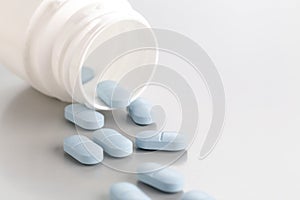 A close-up of a tablet bottle with a few blue antibiotic pills