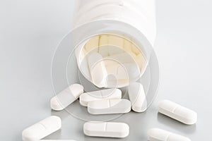 A close-up of a tablet bottle with a few white antibiotic pills