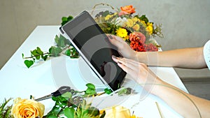 Close-up of tablet on which florist girl`s hands lead fingers am