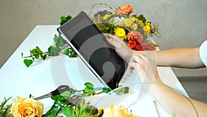 Close-up of tablet on which florist girl`s hands lead fingers am