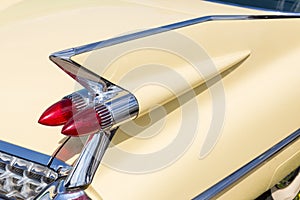 Close-up of tail light and rear part of retro car. Detail of vintage classic vehicle. Wing fender with chrome bumper and red brake