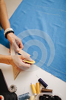 Close up of tailor drawing lines with soap on blue cloth
