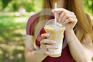 Close up of takeaway cold coffee in womans hands