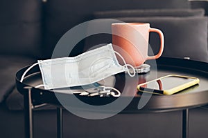 Close up of taken off face mask on coffee table in home interior. New every day normality to prevent to spreading the virus.