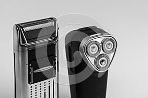 Two different shavers leaning each other on white background